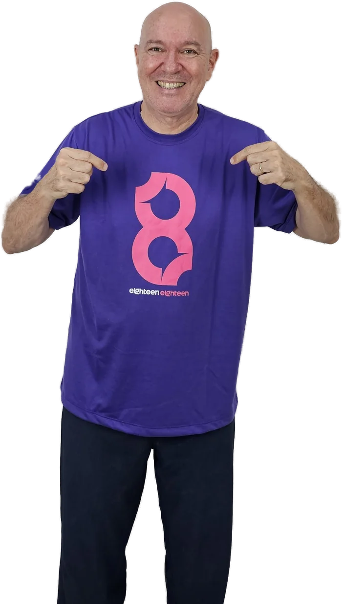 Prof. JH sorrindo e apontando para o logo do Eighteen Eighteen na camiseta