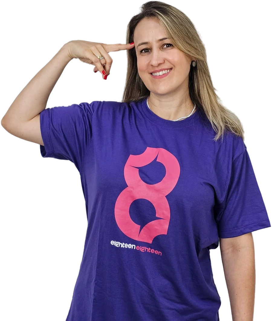 Prof.ª Carla, do Eighteen Eighteen, sorrindo, com a camiseta da escola, apontando para a cabeça